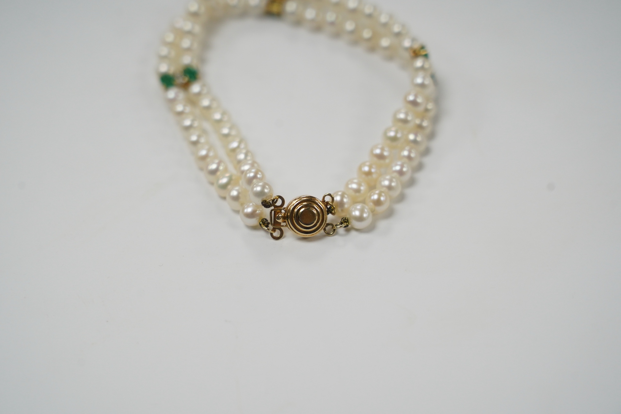 A modern Mexican double strand cultured pearl bracelet, with 14k clasp and emerald and three emerald and diamond cluster set spacers, 17cm. Fair condition.